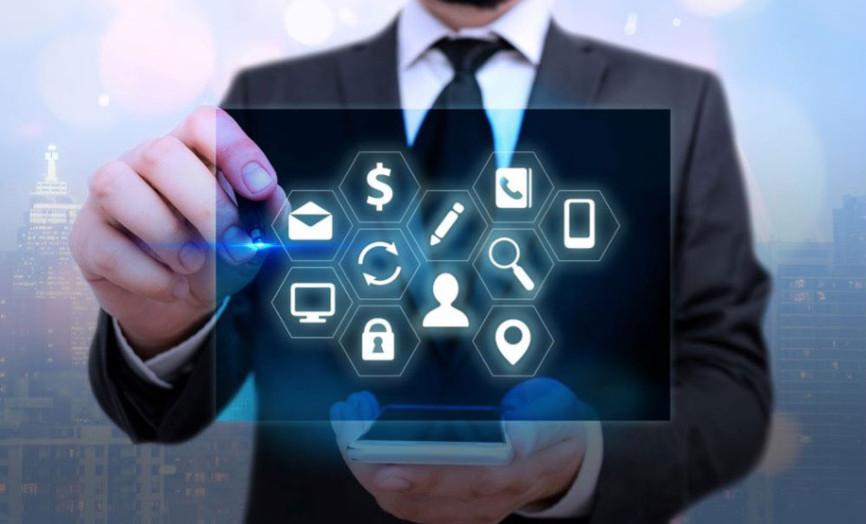 Muž v obleku drží v jedné ruce chytrý telefon a druhou rukou interaktivně ovládá digitální rozhraní s bílými ikonami v šestiúhelnících; ikony symbolizují komunikaci, finance, bezpečnost a data na pozadí rozmazaného panoramatu velkoměsta.