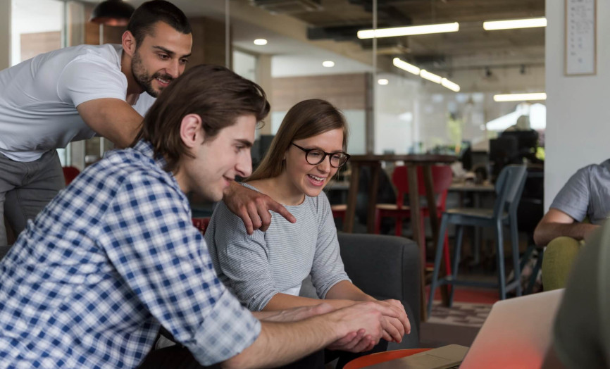 Trojica kolegov v modernej kancelárii spoločne konzultuje projekt nad notebookom – symbol tímovej synergie, inovatívneho prostredia a odborného rastu v Seyfore.