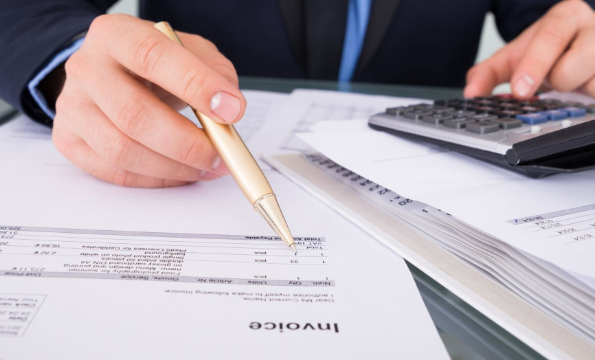 Detail rúk účtovníka pri práci s faktúrami a kalkulačkou – symbol precízneho finančného riadenia, kontroly nákladov a automatizovaného účtovníctva v systémoch Seyfor.