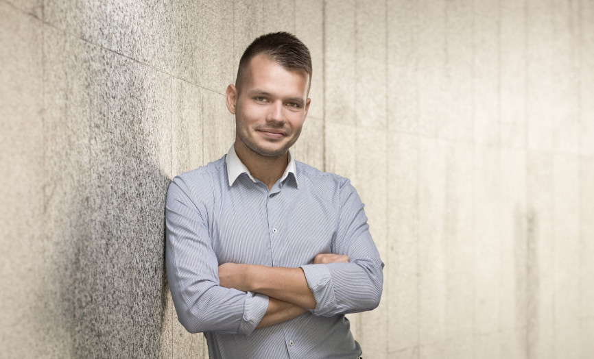 Portrét sebevědomého experta v košili s překříženýma rukama opírajícího se o kamennou stěnu – symbol odhodlání, profesionality a stability týmu skupiny Seyfor.