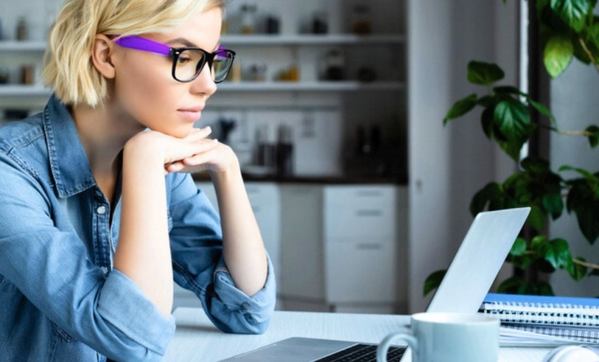 žena v brýlích a modré košili u pracovního stolu