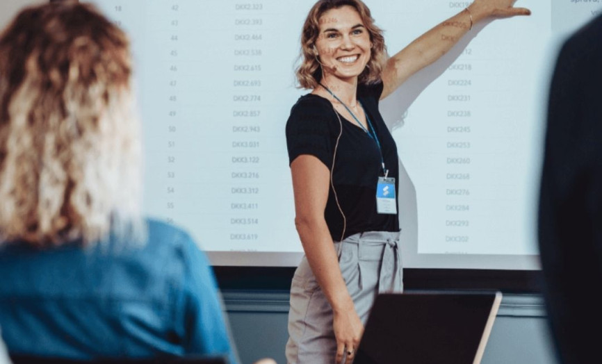 žena s mikrofonem ukazující na tabuli