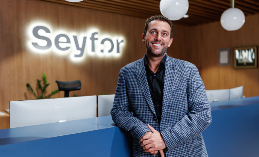 Muž v kostokavén saku opírající se o stůl na recepci