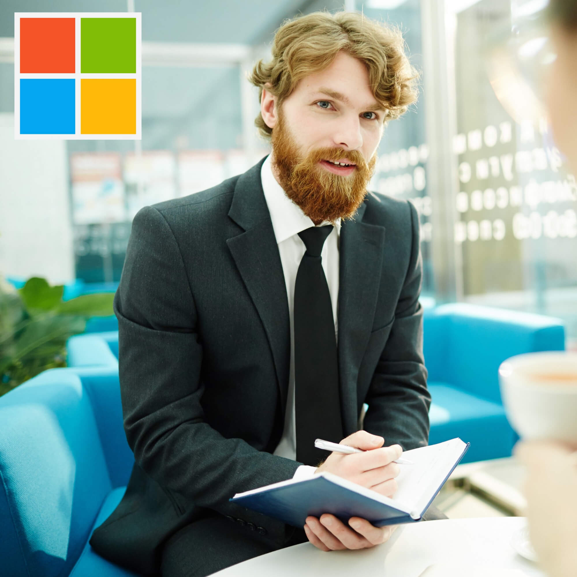 Osoba v obleku píše do bloku na modré pohovce, v rohu logo Microsoft